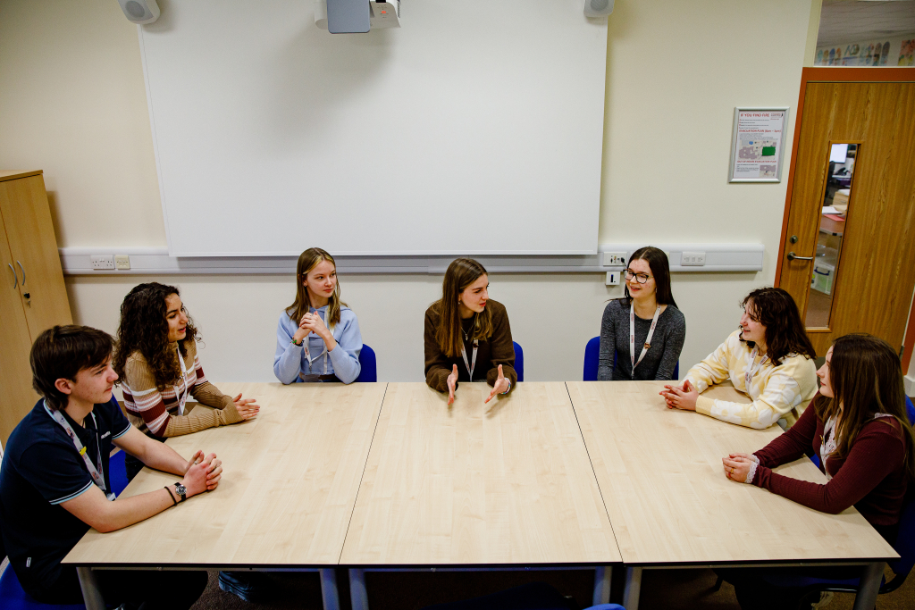 A group of Cowes Enterprise sixth form students have a discussion at a table