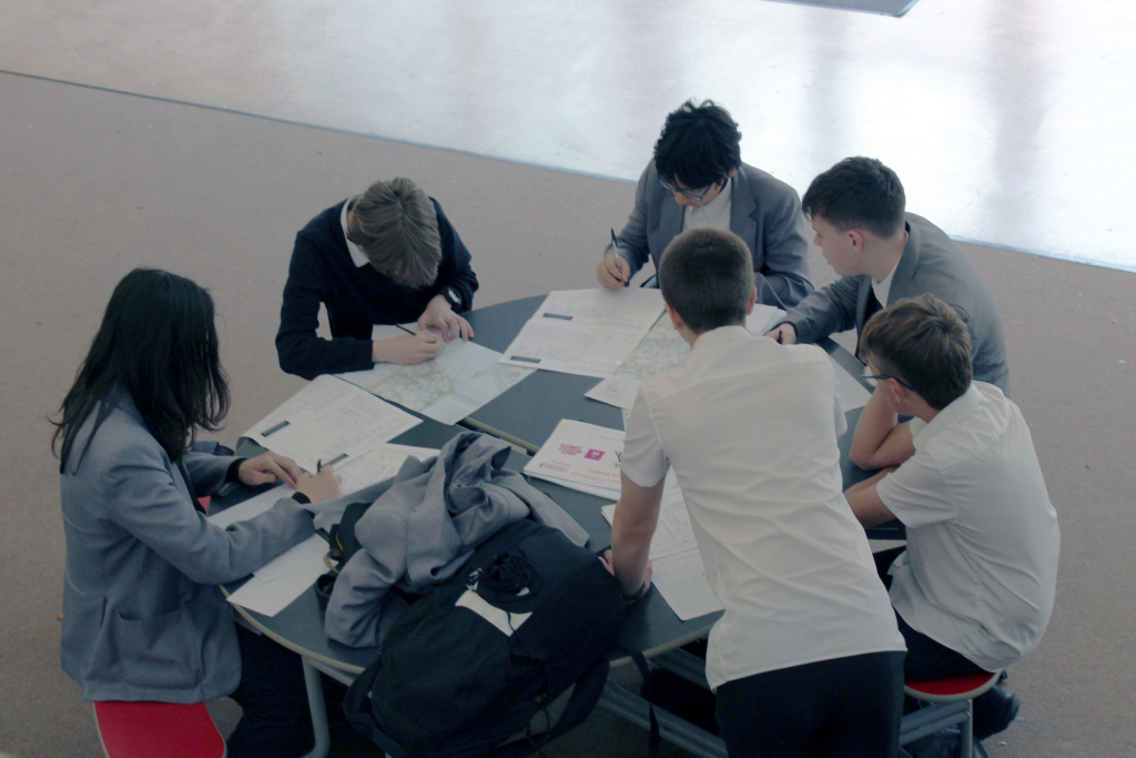 A group of six Cowes Enterprise College students work on route planners and ordinance survey maps around a round table for their Duke of Edinburgh Award walks.