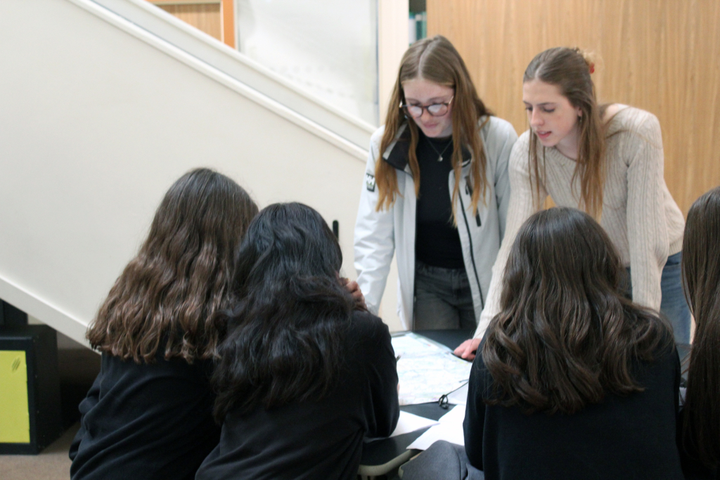 Two female Sixth Form student leaders work with younger students on route planning for the Duke of Edinburgh's award.